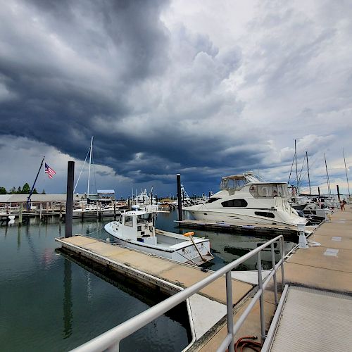 The image shows a marina with several docked boats under a cloudy, possibly stormy sky, and an American flag is visible on the left side of the scene.