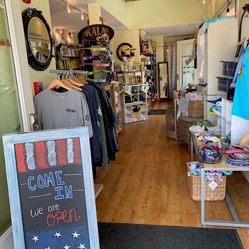 The image shows the interior of a small store with clothing and accessories, a chalkboard sign indicating 